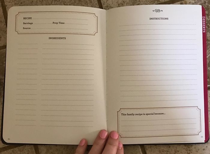 A hand holding up the family recipe book, showing the space available to write down ingredients and instructions.