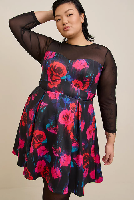A model wearing the dress featuring a rose design with black mesh sleeves