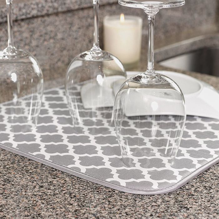 A pair of wine glasses resting on a drying mat featuring a white and gray trellis pattern.