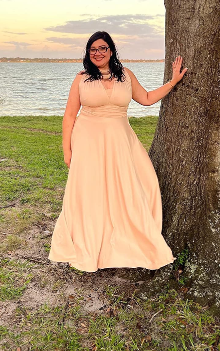 A reviewer showcasing the dress in a soft peach/light pink shade.