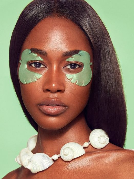 A model is seen wearing eye masks shaped like monstera leaves.