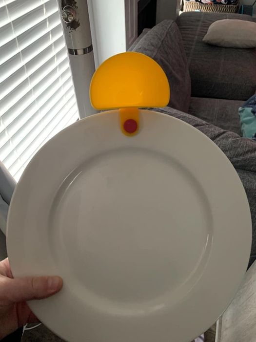 A yellow dip clip attached to a white plate, keeping dips secure and easily accessible.