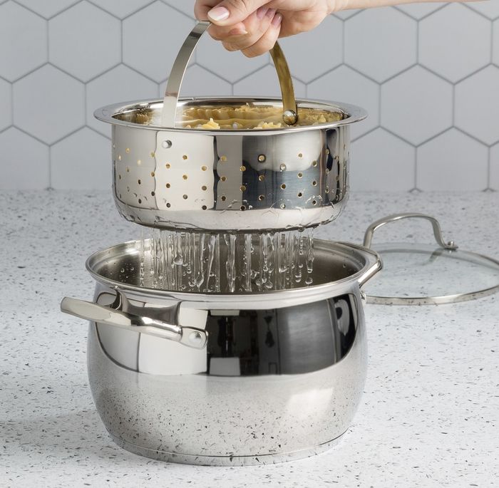 A large stainless steel pot rests underneath a smaller one with holes, draining pasta.