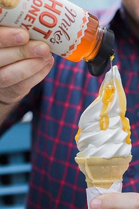 Pouring Mike's Hot Honey onto an ice cream cone for a sweet and spicy twist.