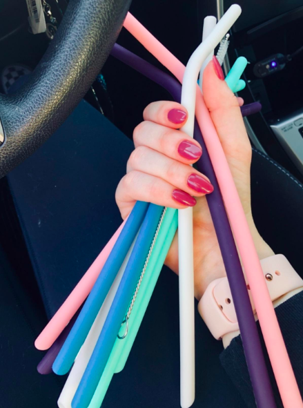 A hand holding several silicone straws in various colors, perfect for any eco-conscious drinker.