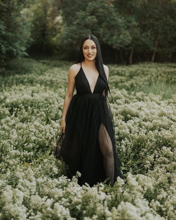 A reviewer surrounded by flowers wearing the black dress.