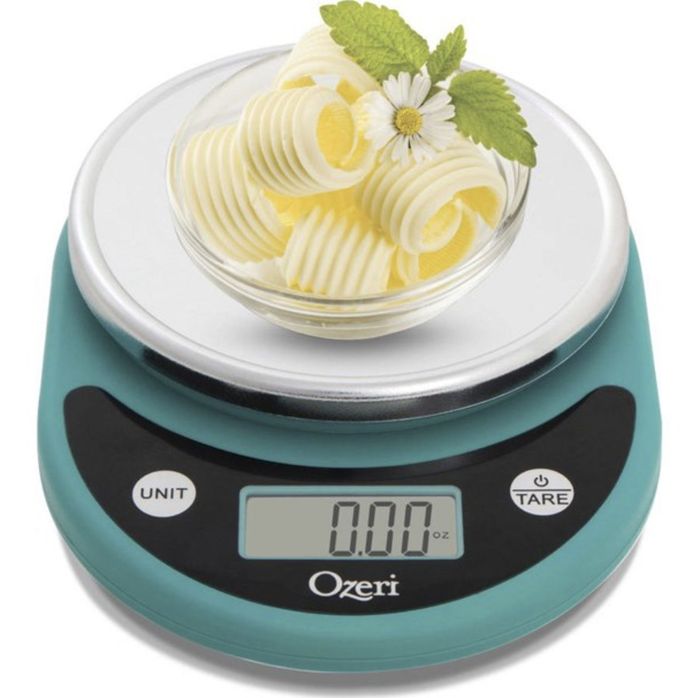The blue and black scale, topped with spirals, a bowl of butter, mint, and a flower, is shown in the image.