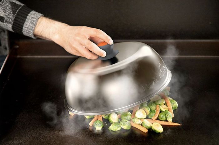 The silver dome lid is steaming a medley of vegetables.