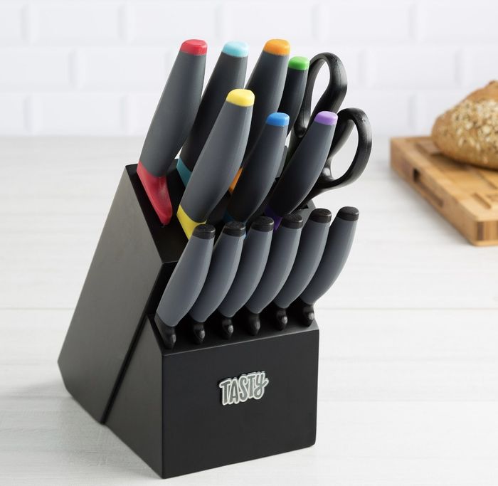 The sleek black knife block proudly displays the word 'TASTY,' with knives featuring a variety of colorful handles.