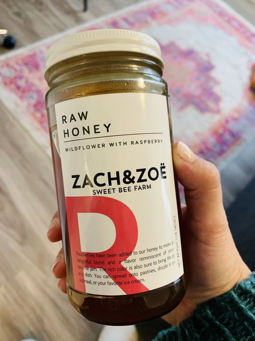 writer holding up a jar of raspberry wild honey from Zach & Zoë