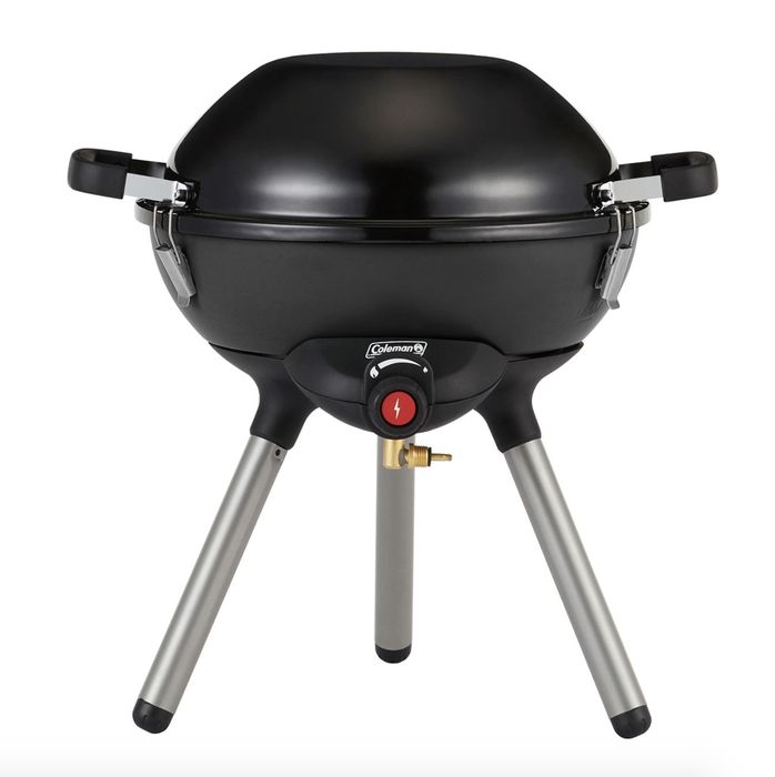 The black grill features the name 'Coleman' on its surface and stands on three silver legs.