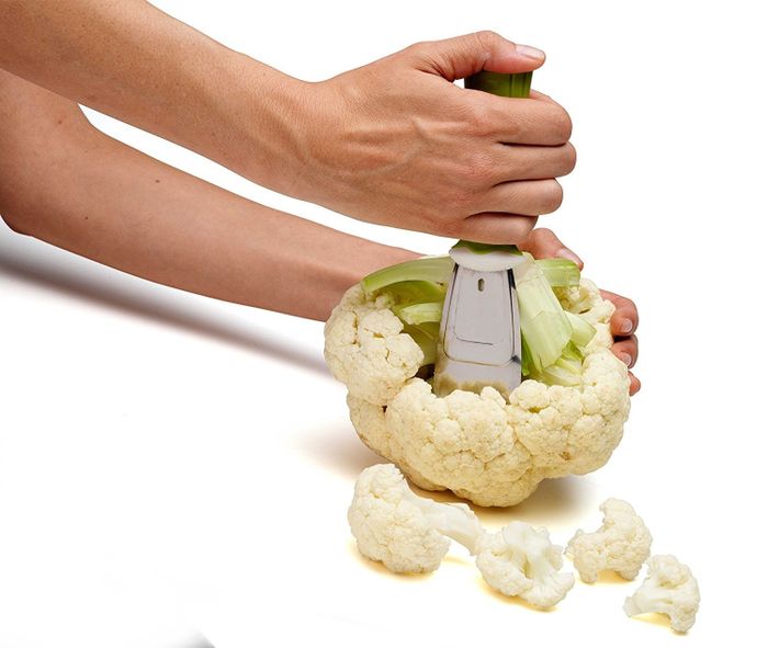 A hand using a tool to chop through a fresh cauliflower head with ease.