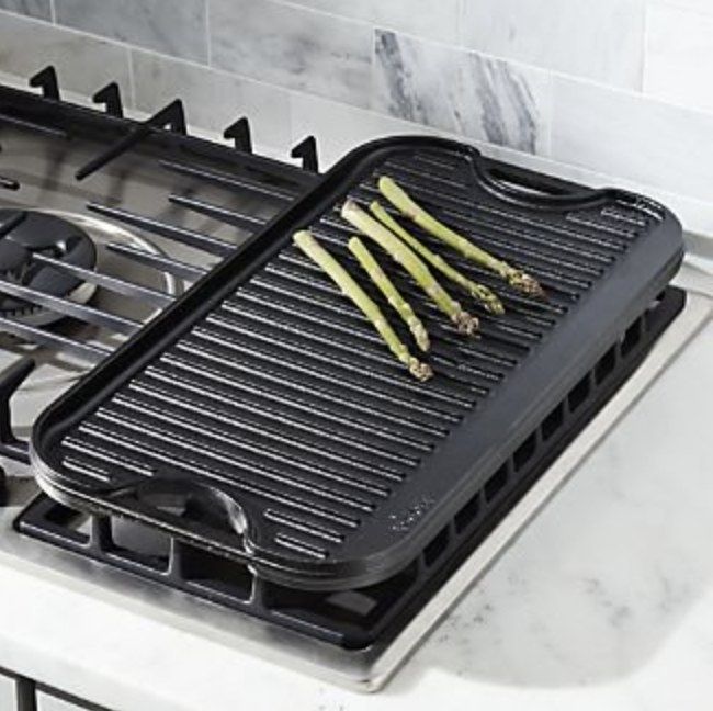 The black cast iron griddle with asparagus sizzling on top.