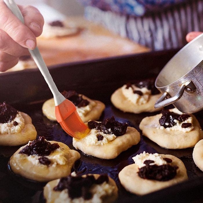 A basting brush delicately applying an egg wash to golden pastries before baking.