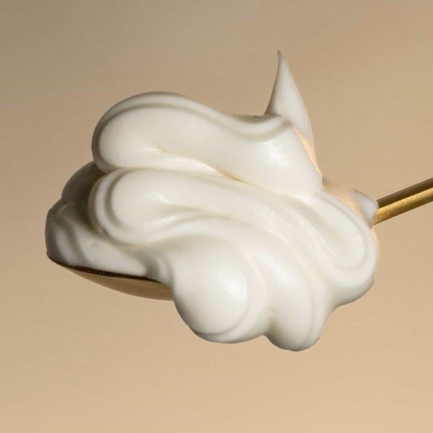 A spoon holds a generous scoop of whipped cream.