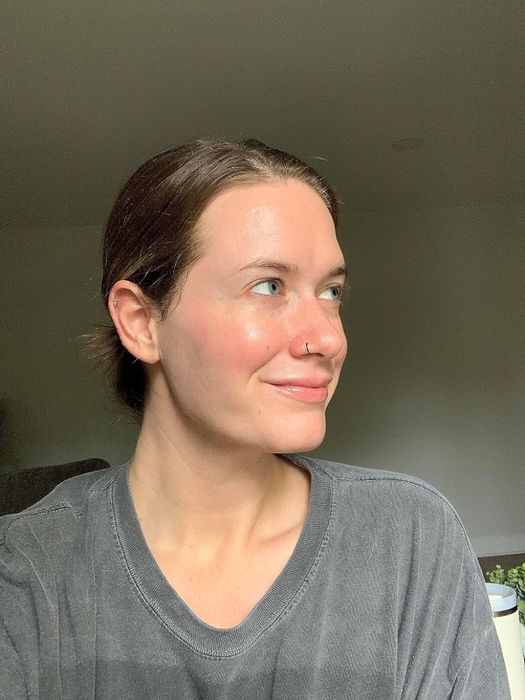 A person sporting a nose ring and dressed in a casual T-shirt gazes to the right with a subtle, warm smile.