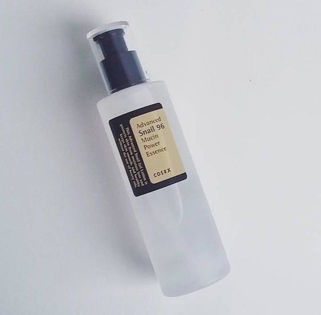 A bottle of COSRX Advanced Snail 96 Mucin Power Essence featuring a sleek white pump top, showcased against a clean white background.
