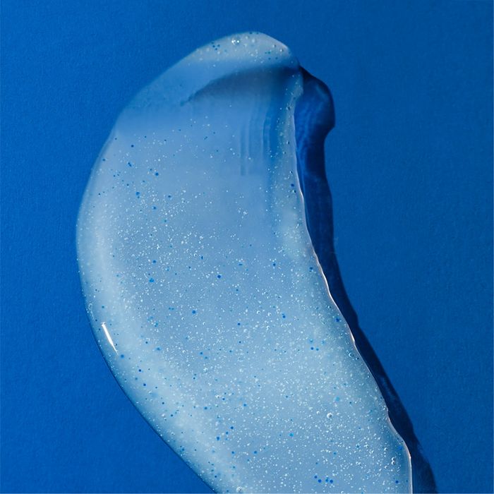 A translucent gel with tiny bubbles and sparkles is smeared across a solid blue background, creating a visually striking image.