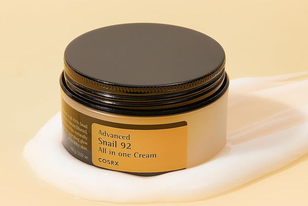 COSRX Advanced Snail 92 All in one Cream presented in a jar with a black lid, displayed alongside a sample of the cream, emphasizing its role in a comprehensive skincare routine.