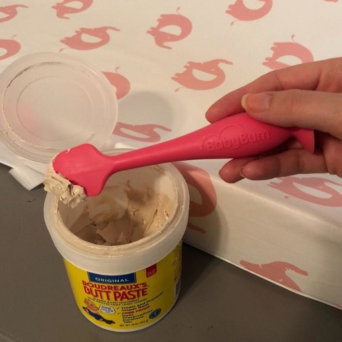 A reviewer holding the pink applicator above a jar of cream.