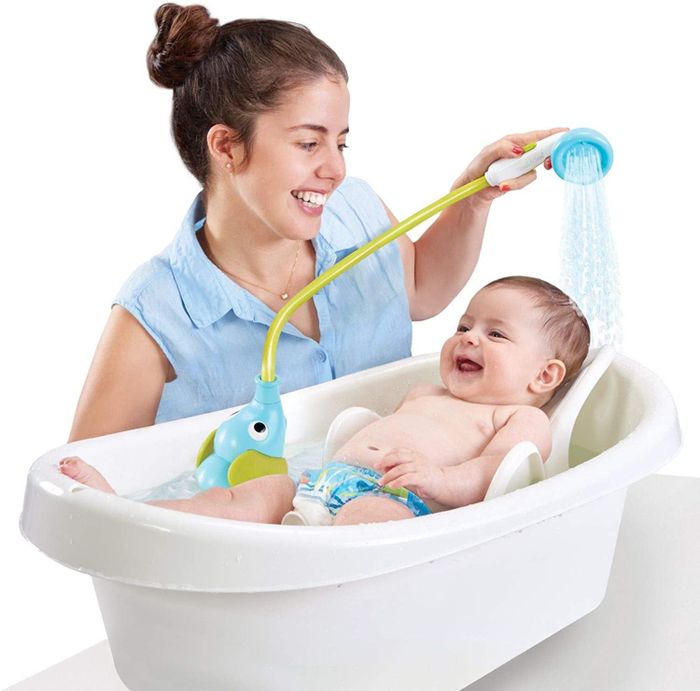 A parent using the elephant bath sprayer on their child during bath time.