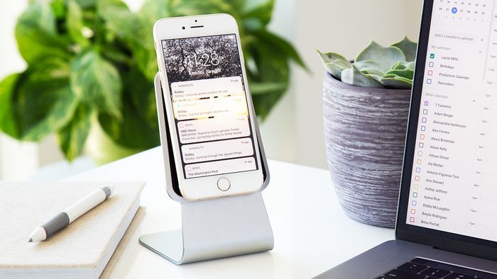 An iPhone resting securely on a slanted tablet stand with no ledge to support it.