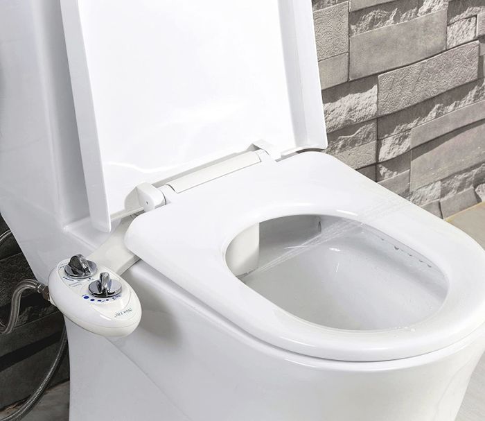 The bidet, securely attached to the side of a toilet.