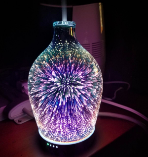 A reviewer's diffuser glowing in the dark, displaying cool-toned lights in a stunning firework pattern.