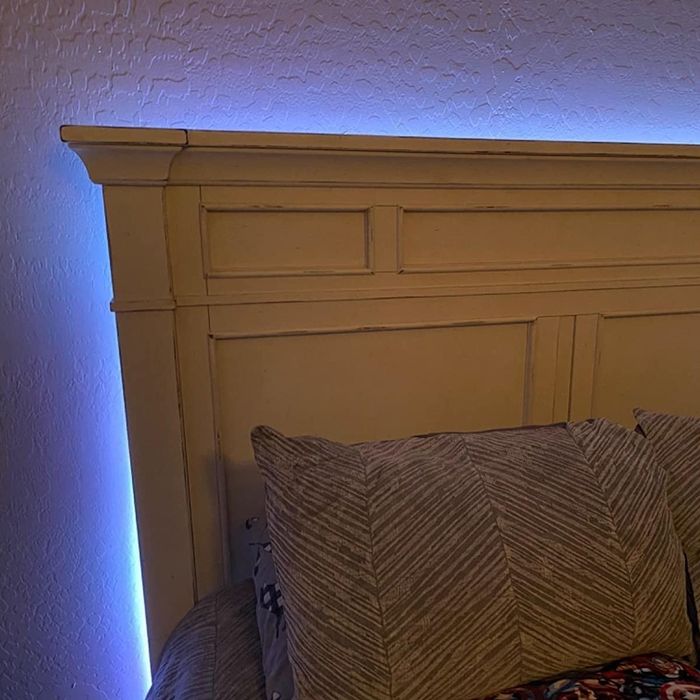 The light strips neatly tucked behind a headboard, leaving only the soft glow visible.