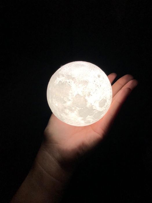 A reviewer holding the moon light in their hand, demonstrating different color and brightness settings.