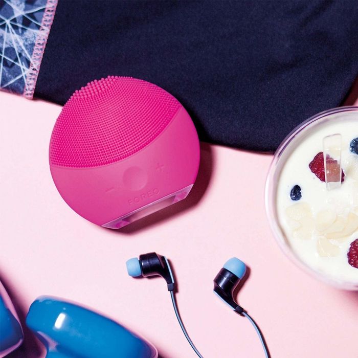 A round silicone facial cleansing brush, featuring densely packed, short bristles on the upper half.