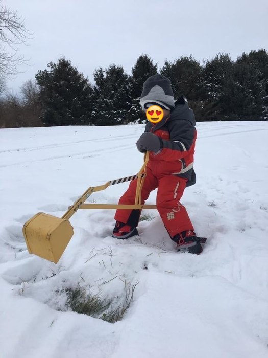 A child enjoys playing with the digger, even in snowy conditions.