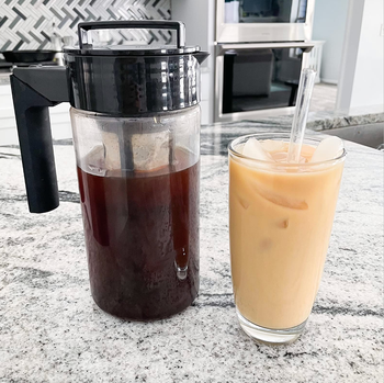 The pitcher filled with cold brew sits next to a cup of refreshing iced coffee.