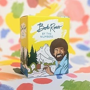 The box of a Bob Ross paint-by-numbers kit featuring his illustration with mountains and trees in the background