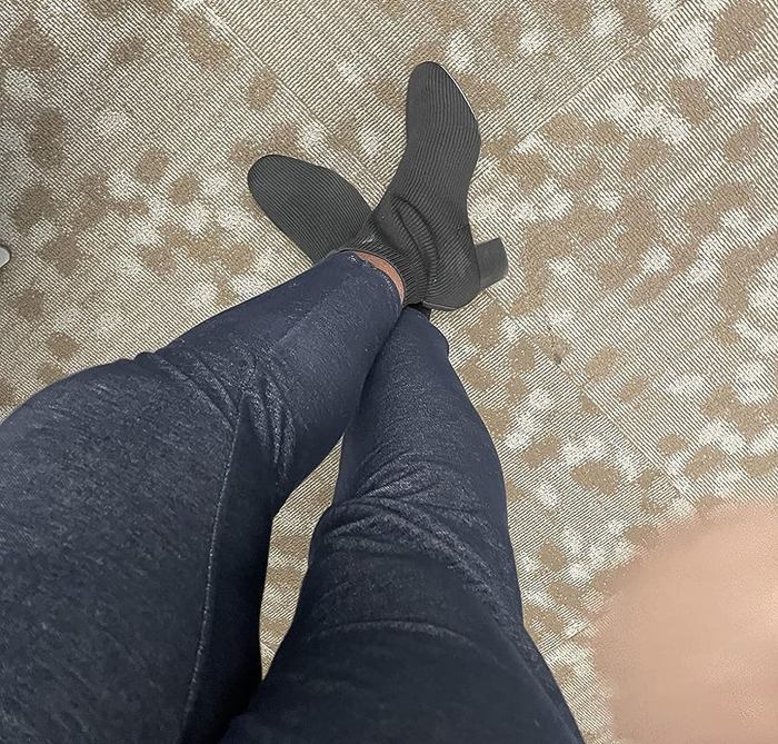 A reviewer showcasing the black version of the knit booties