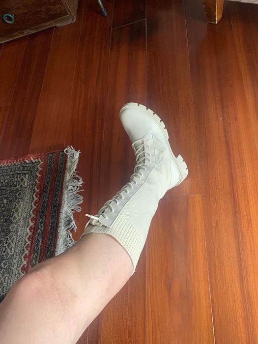 A reviewer is showcasing one of their legs while wearing a cream-colored version of the boots.