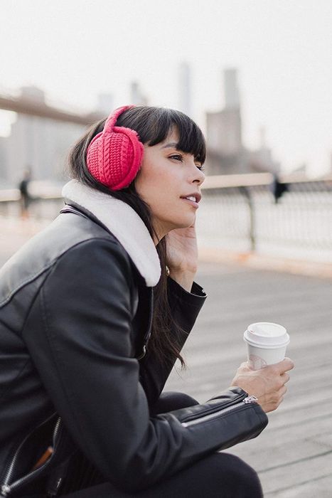 A model wearing the red earmuffs with a cozy knit exterior and soft fur lining