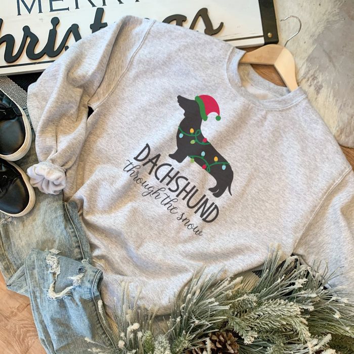The grey sweatshirt featuring a dachshund wrapped in Christmas lights and the words 