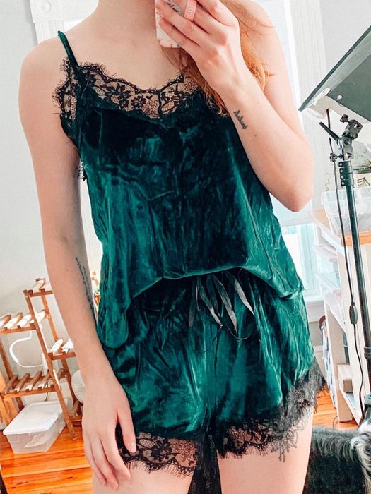 A reviewer in a green velvet tank top and matching shorts set with black lace details