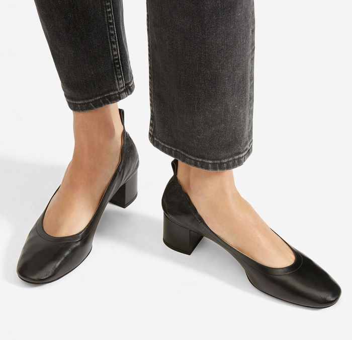 A model is wearing black jeans paired with black square-toe block heels.