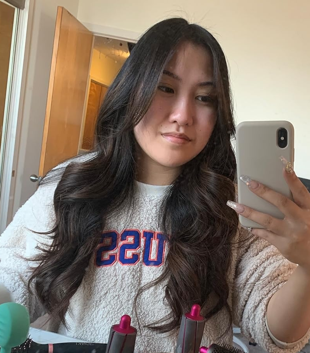 a reviewer of color with subtle waves in their long, dark, glossy hair