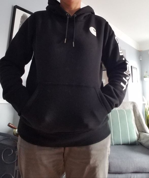 A reviewer sporting a black hoodie paired with brown trousers.