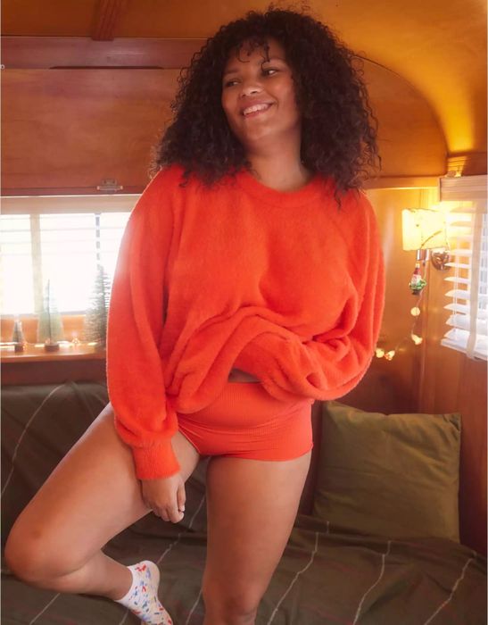 A model wearing a vibrant orange top with matching bottoms