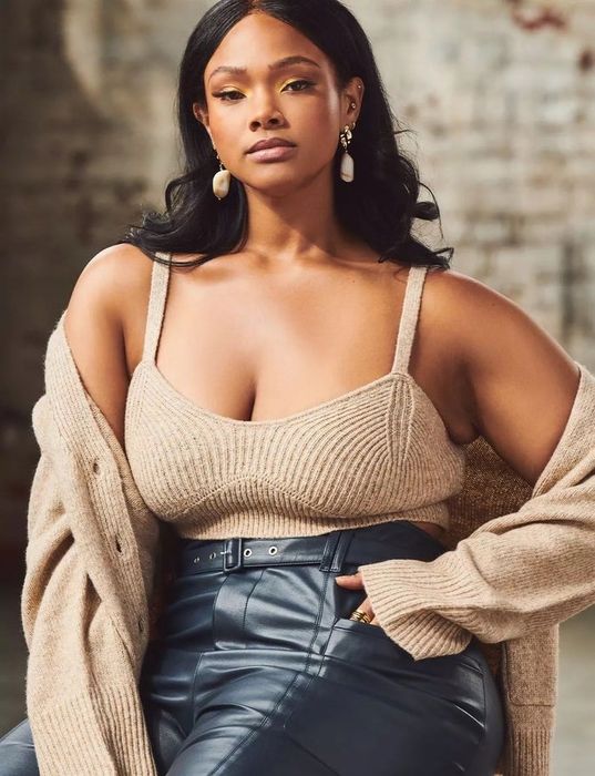 A model showcasing the beige bralette paired with a matching sweater and black leather pants