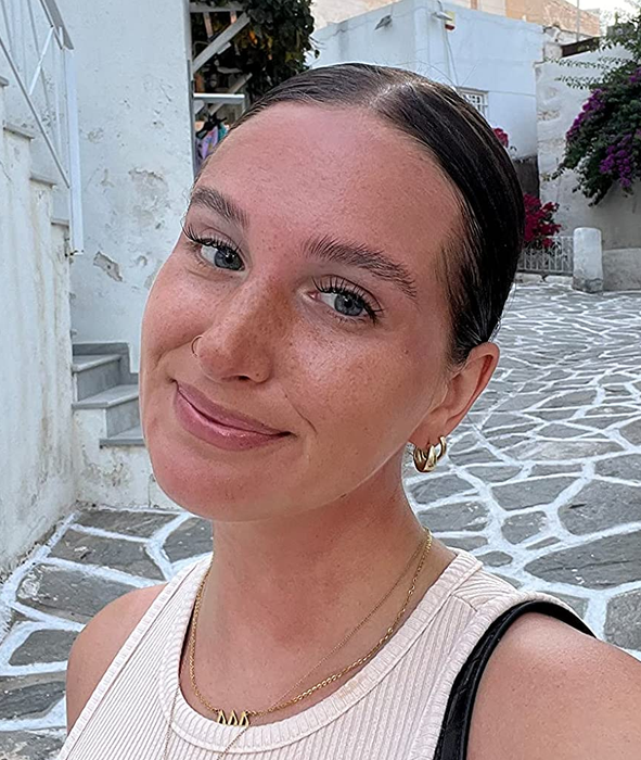 A reviewer with a sleek, slicked-back bun after using the hair wax stick for control.