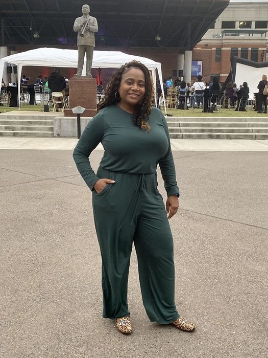 A reviewer styled in a green jumpsuit paired with animal-print shoes