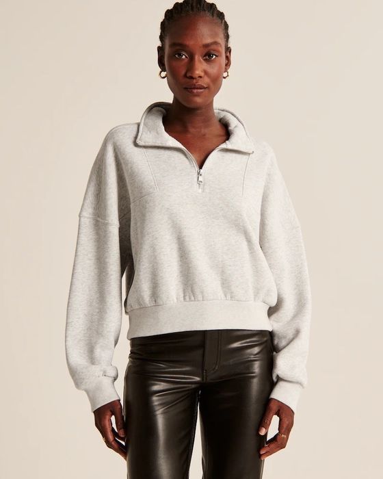 Model dressed in a grey quarter-zip paired with black trousers