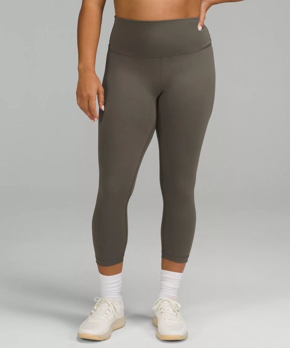 A model showcasing grey-beige pants paired with white socks and sneakers