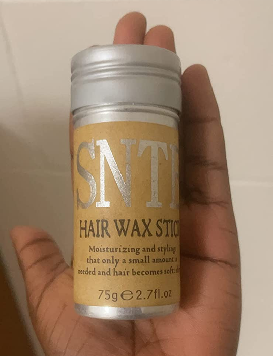 A reviewer holding up the hair wax stick, ready to style.