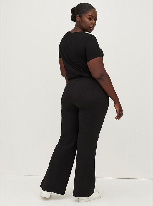 The back view of the model wearing black flared pants.